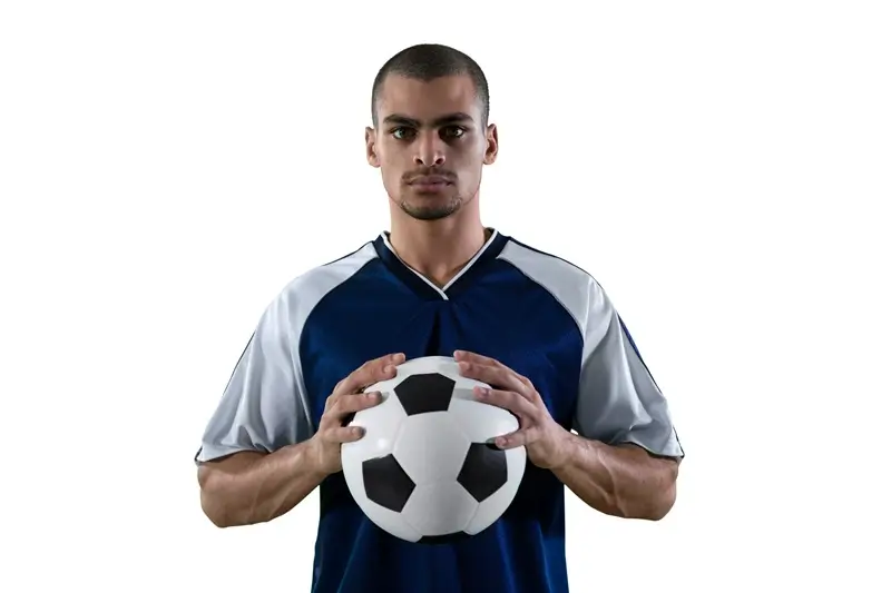 Jogador de futebol canhoto segurando futebol com as duas mãos