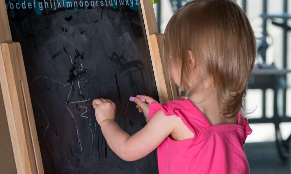 criança ambidestra escrevendo no quadro