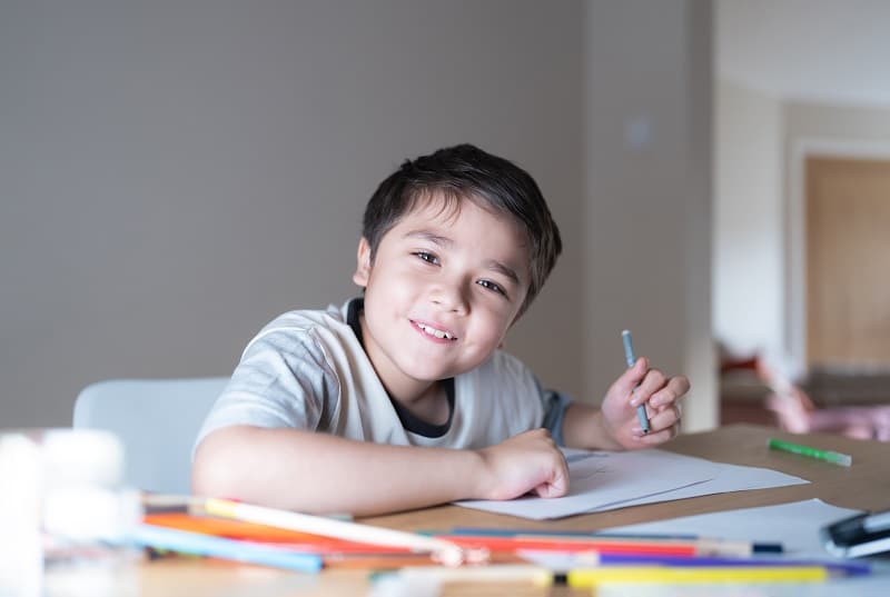 criança da escola usando caneta de cor cinza na mão esquerda