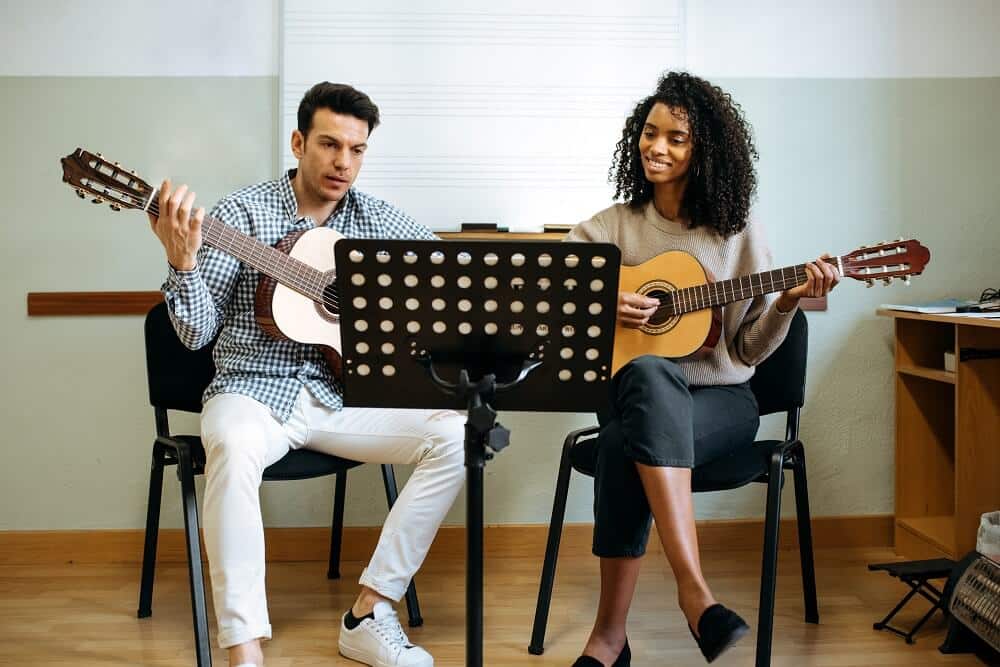 homem canhoto e mulher destra tocando violão no estúdio